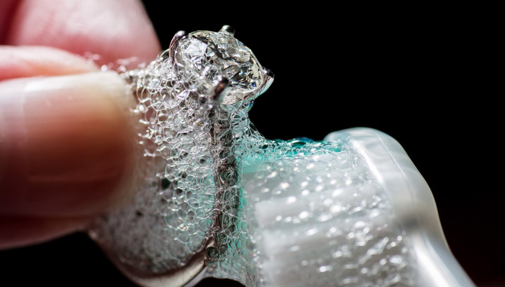 cleaning a ring with soapy water and a tooth brush