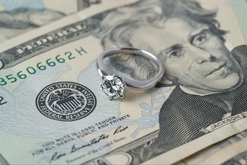 An engagement ring atop a $20 bill