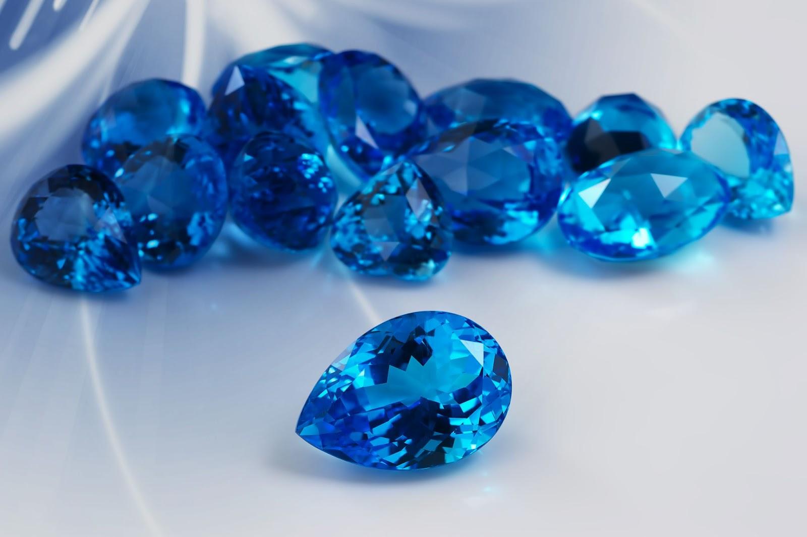 Different cuts of light blue topaz against a blue and gray gradient background