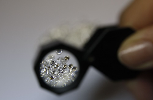 Jeweler looking at loose diamonds through tool