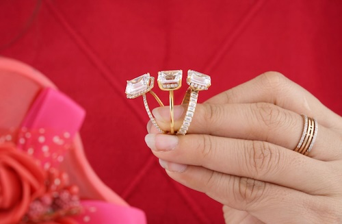 woman holding three diamond rings in fingers