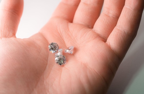 person holding loose diamond in palm
